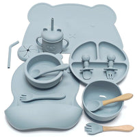 Ensemble repas complet en silicone – Édition Ourson, comprenant 10 pièces en silicone sans BPA : assiette compartimentée, bols, gobelet à paille, couverts bois‑silicone et tapis en forme d’ourson, le tout dans une teinte douce et chaleureuse.