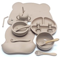 Ensemble repas complet en silicone – Édition Ourson, comprenant 10 pièces en silicone sans BPA : assiette compartimentée, bols, gobelet à paille, couverts bois‑silicone et tapis en forme d’ourson, le tout dans une teinte douce et chaleureuse.